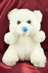 ourson blanc sur fond de satin rouge