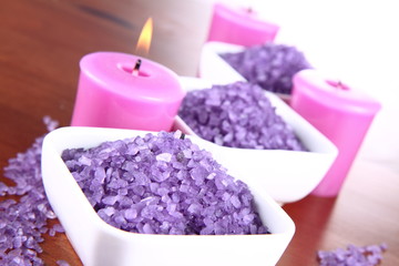 Lavender spa salt and lavender candles on a wooden background