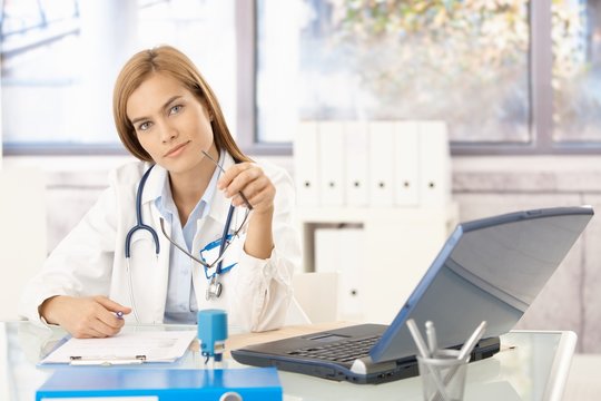 Attractive doctor writing report sitting at desk
