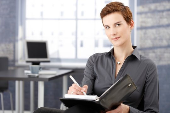 Smiling businesswoman writing notes