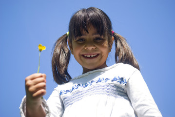 Girl holding flower. Portrait against blue sky