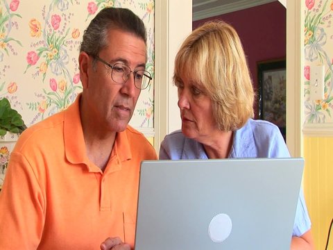 Mature couple making purchase with laptop