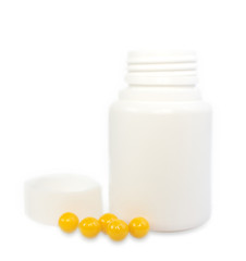 few yellow coated tablets on a background of white plastic jars