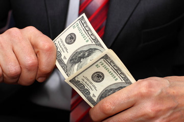 Businessman putting dollar banknotes.