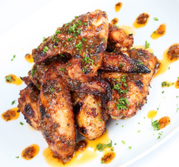 Hot grilled chicken wings on white plate with drizzle of sauce