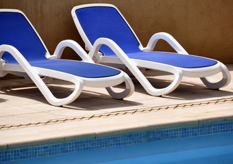Chaises longues bleus au bord d'une piscine