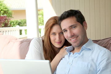 Couple sitting in couch with laptop computer
