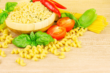 spaghetti with basil leaves, tomatoes and pepper on a yellow bac