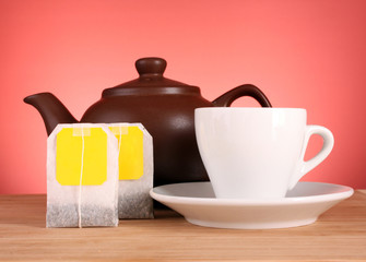 Close-up of tea bag and teapot on yellow background