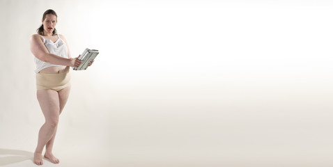 Übergewichtige erwachsene Frau hält eine Waage