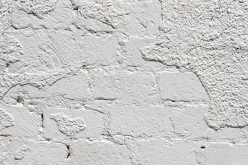 white wall of limestone blocks with parts of peeled plaster