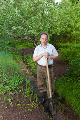 Man digs up a garden-bed with the first sprouts