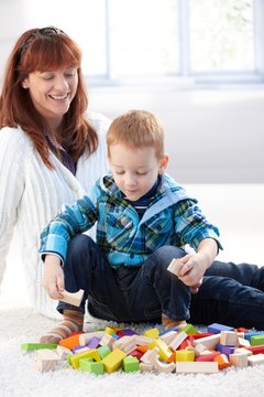 Little boy playing with cubes mother watching