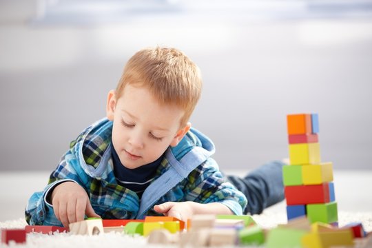 Lovely toddler playing with building cubes at home