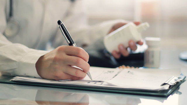 Female doctor hands writing rx prescription