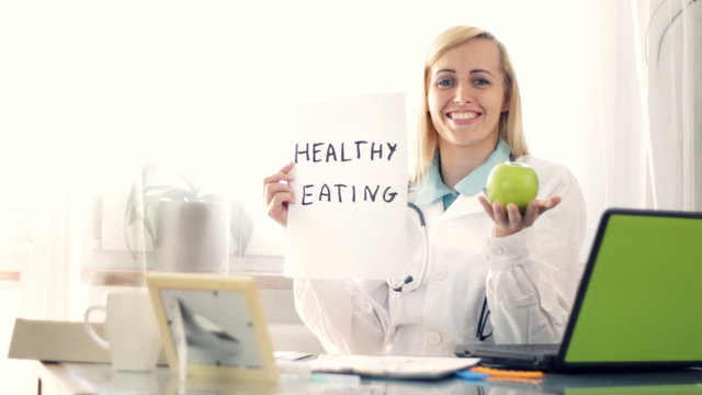 doctor holding apple and paper sheet with HEALTHY EATING
