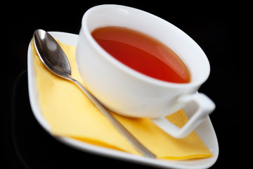 Tea cup and tea spoon on black background