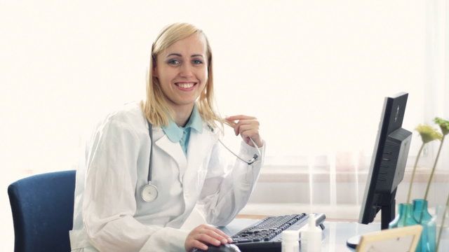 Portrait of happy smiling female doctor working on computer