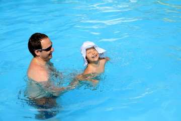 Dad teaches his daughter to swim in the pool © aglebocka