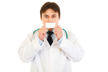 Medical doctor holding blank business card in front of mouth