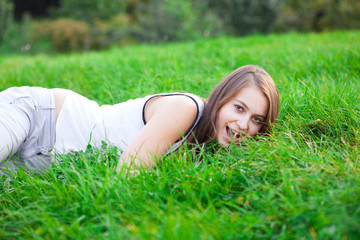 beautiful young woman lying on green grass