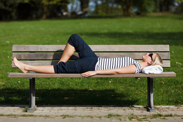 frau liegt schlafend auf einer parkbank