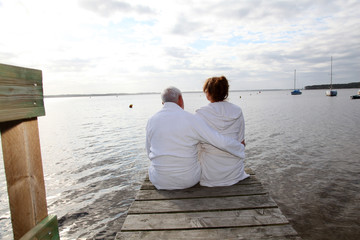 Senior couple in bathrobe sitting on a pontoon