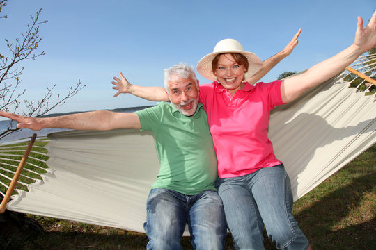 Happy senior couple sitting in hammock