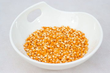 Pile of popcorn seeds isolated on white bowl