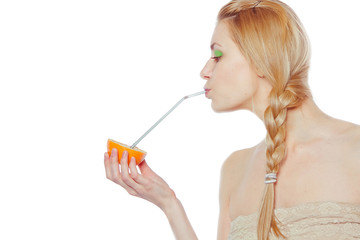 woman drinking juice direct from an orange fruit using a straw