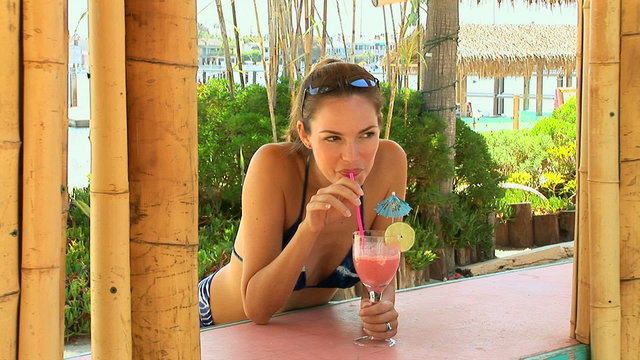 Young Woman By Cabana Sipping A Tropical Drink