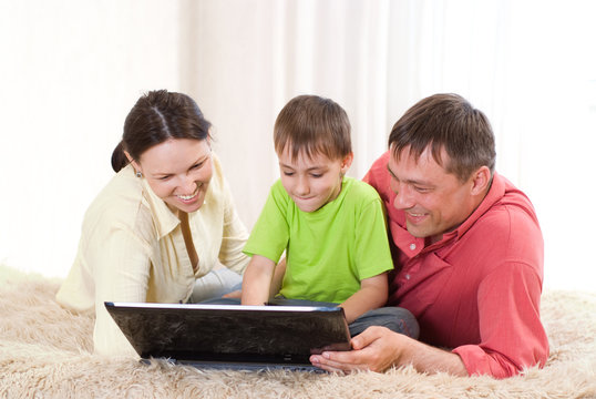 happy boy with laptop with parents
