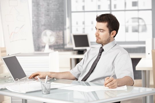 Young businessman working in office using laptop