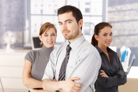 Young colleagues standing in office arms crossed