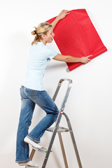 frau bringt eine tapete an die wand