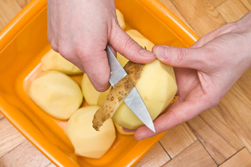 woman's hands peeling potatoes with a knife