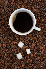 Coffee cup with sugar on roasted beans