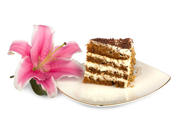 Piece of cake on a plate and a beautiful pink lily