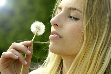 Junge Frau mit einer Pusteblume