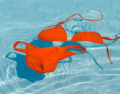 Orange bikini in clean water. Swim suit in turquoise pool.