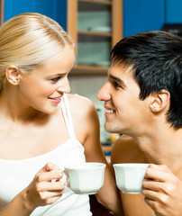 Young happy smiling couple drinking coffee together at home