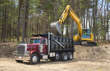 Fotobehang Vrachtwagen Excavator loading dumper truck with dirt at construction site  © Christian Delbert