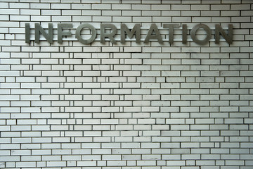 Information Sign on White Brick Wall