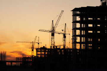 construction site with construction cranes at sunset