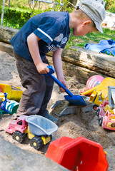 Junge schaufelt Sand auf Laster