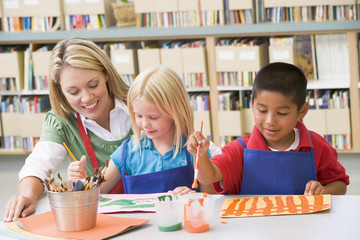 Kindergarten teacher sitting with students in art class