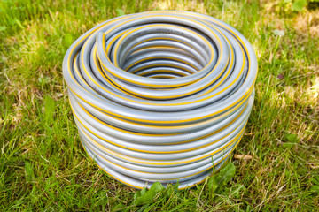 Grey plastic water hose on green grass