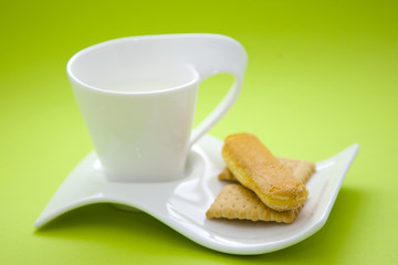 cup with milk and cookies over geen background