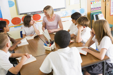 Schoolchildren and their teacher reading books in class