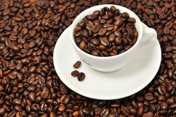 Cup with coffee beans on coffee background